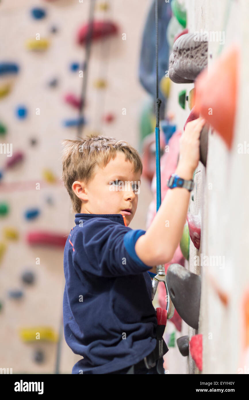 Caucasian boy climbing rock wall indoors Stock Photo