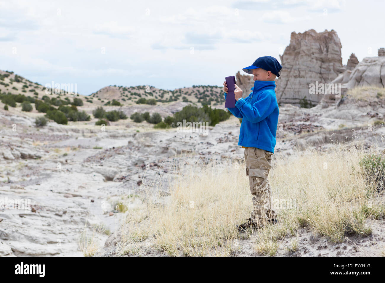 Boy photographing rock formations in desert landscape Stock Photo