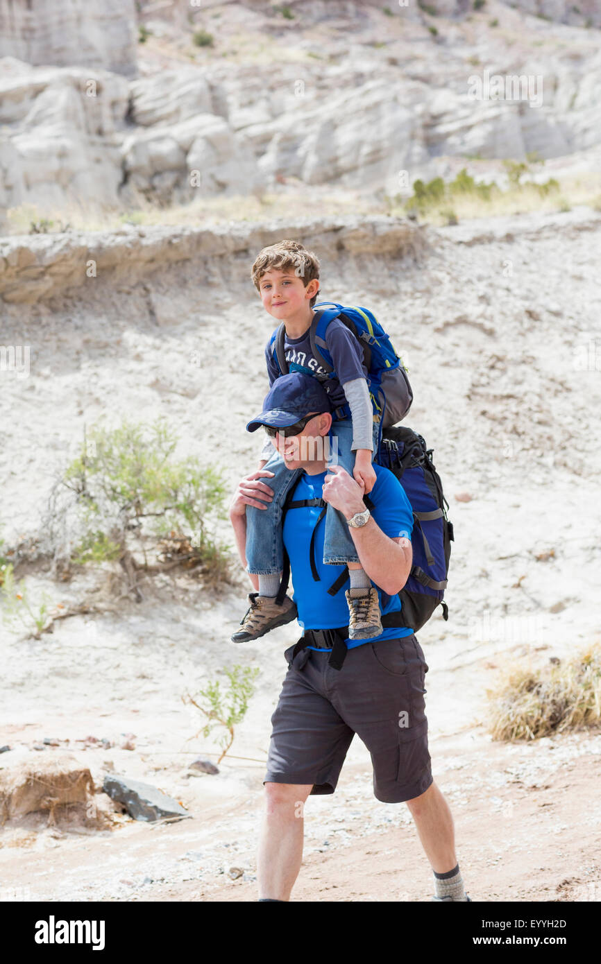Caucasian father carrying son on shoulders on dirt path Stock Photo