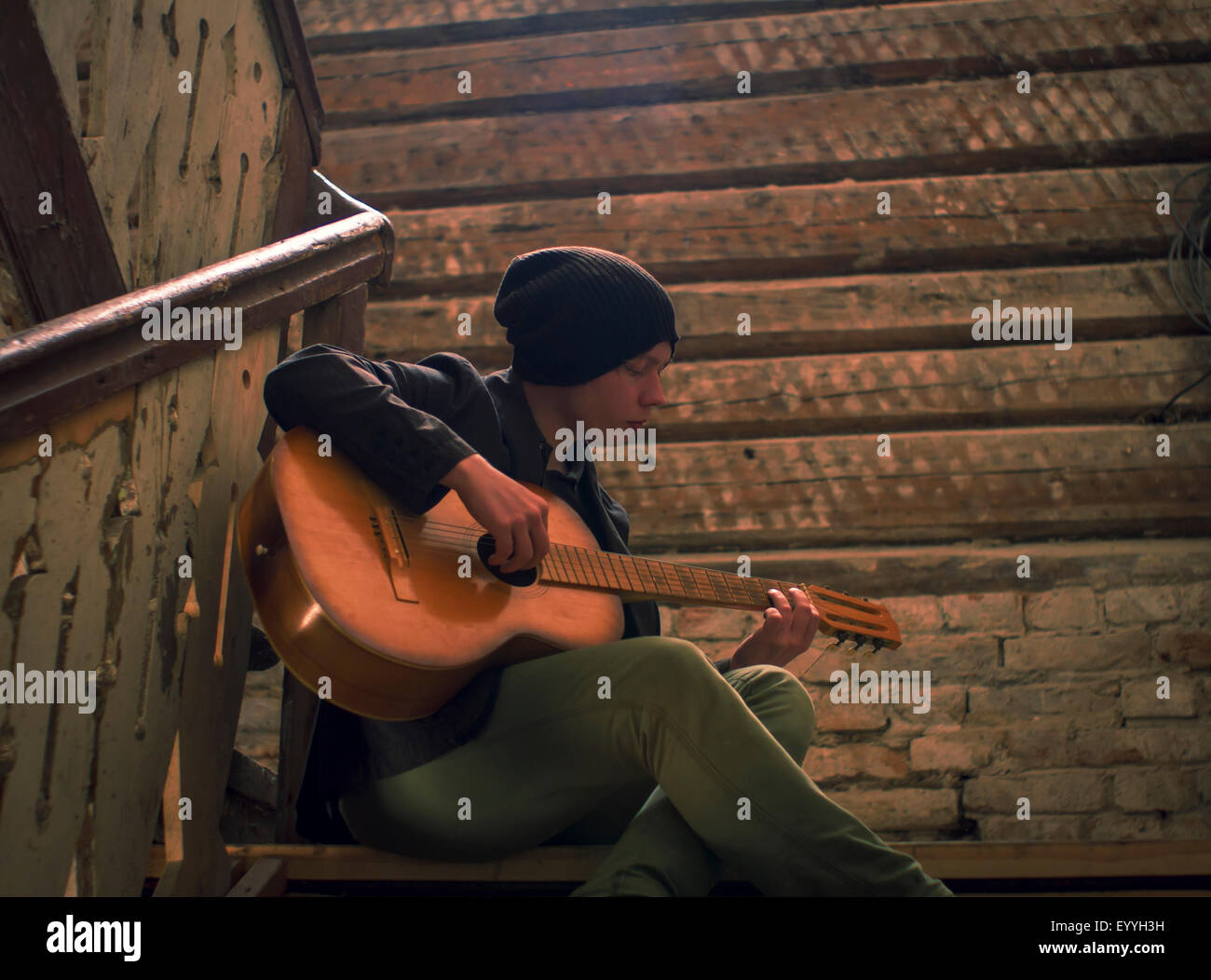 Caucasian man playing guitar on staircase Stock Photo