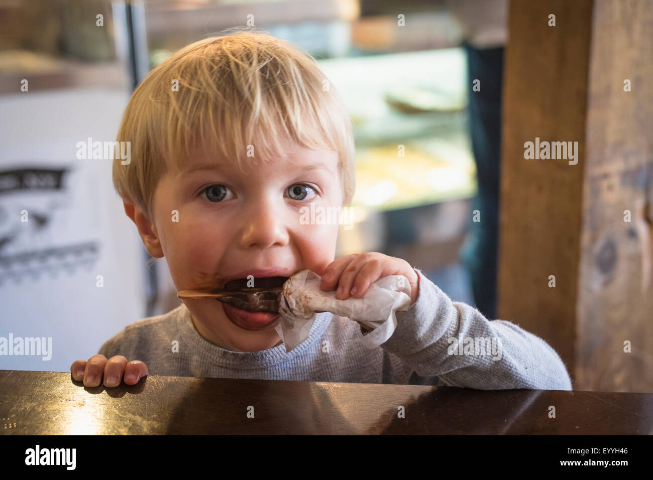 Messy Caucasian boy eating popsicle in kitchen Stock Photo