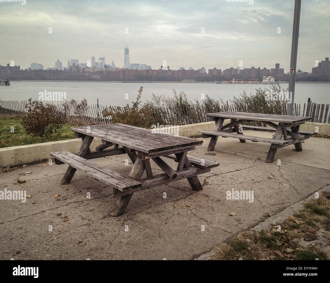 Empty picnic tables in urban park at waterfront Stock Photo