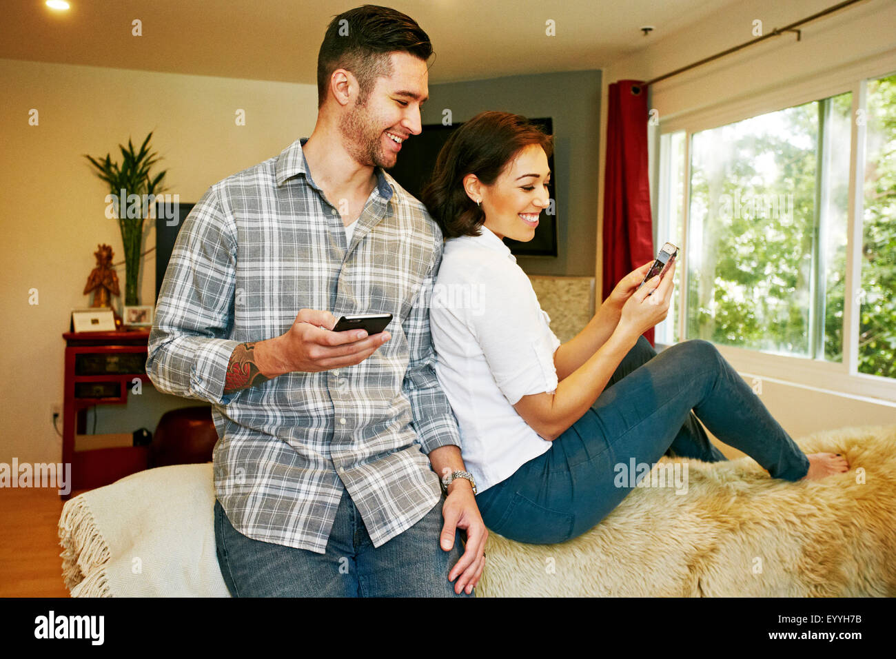 Couple using cell phones on sofa in living room Stock Photo Alamy