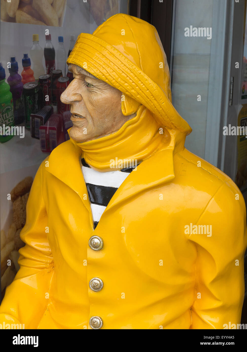 A painted sculpture of a fisherman wearing bright yellow waterproofs and sou'wester outside a Norfolk  cafe England Stock Photo