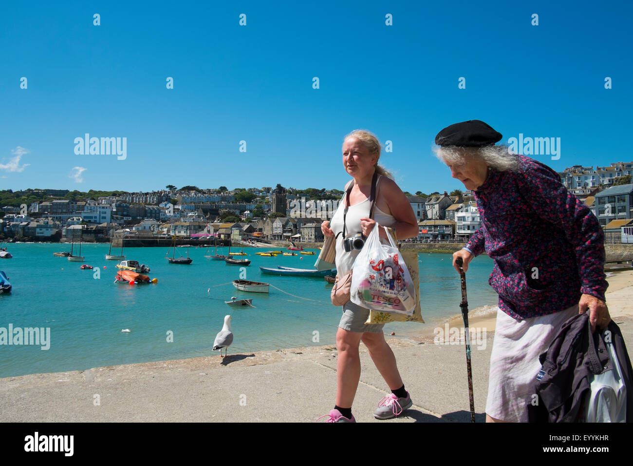 Two women walking along the seafront at St Ives, Cornwall, England, UK Stock Photo