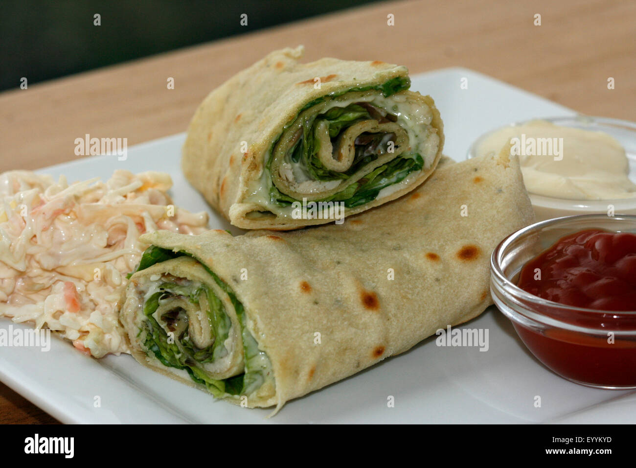 A chicken & pesto wrap with coleslaw, ketchup and mayonnaise Stock Photo