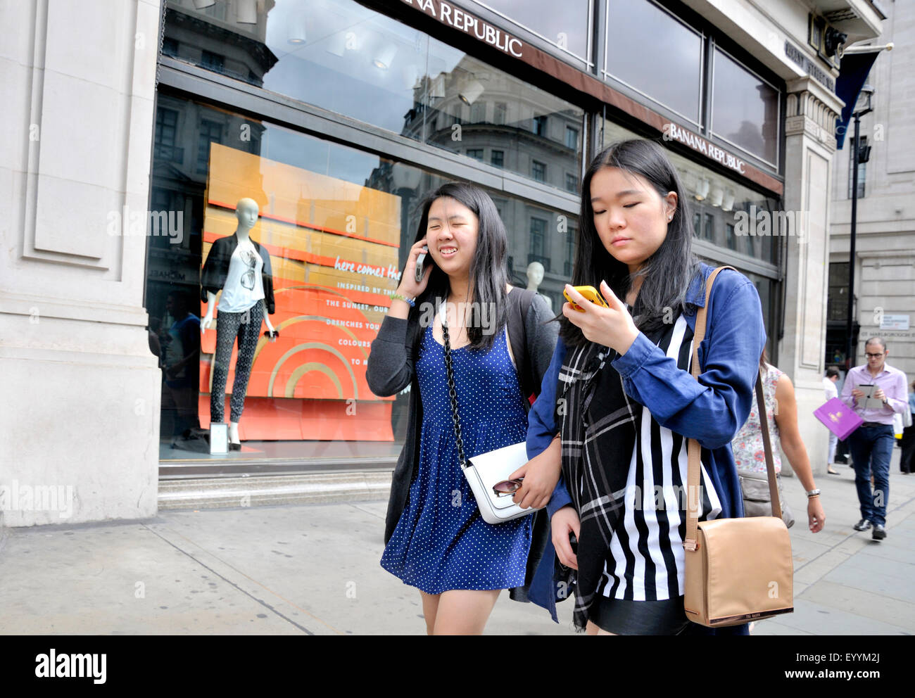 London, England, UK. Two young Japanese women on their mobile phones Stock Photo