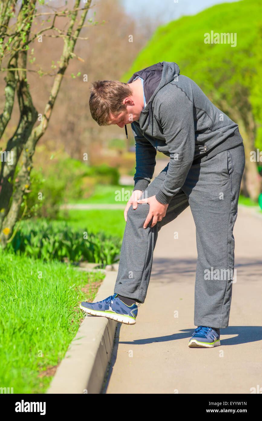 male athlete rubbing his sore knee Stock Photo Alamy