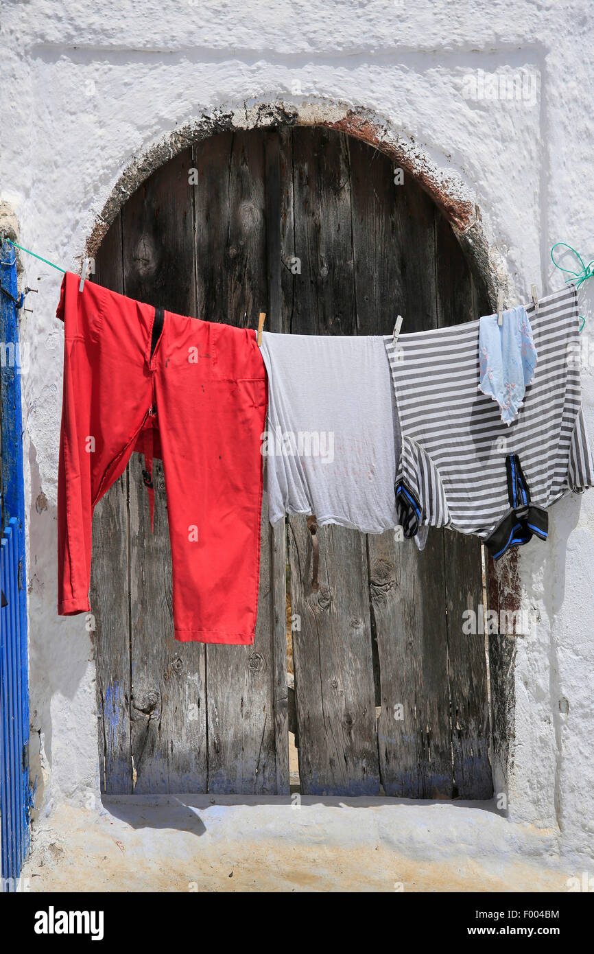 coloured washing hanging on a clothesline in front of an old wooden door, Greece, Cyclades, Santorin Stock Photo