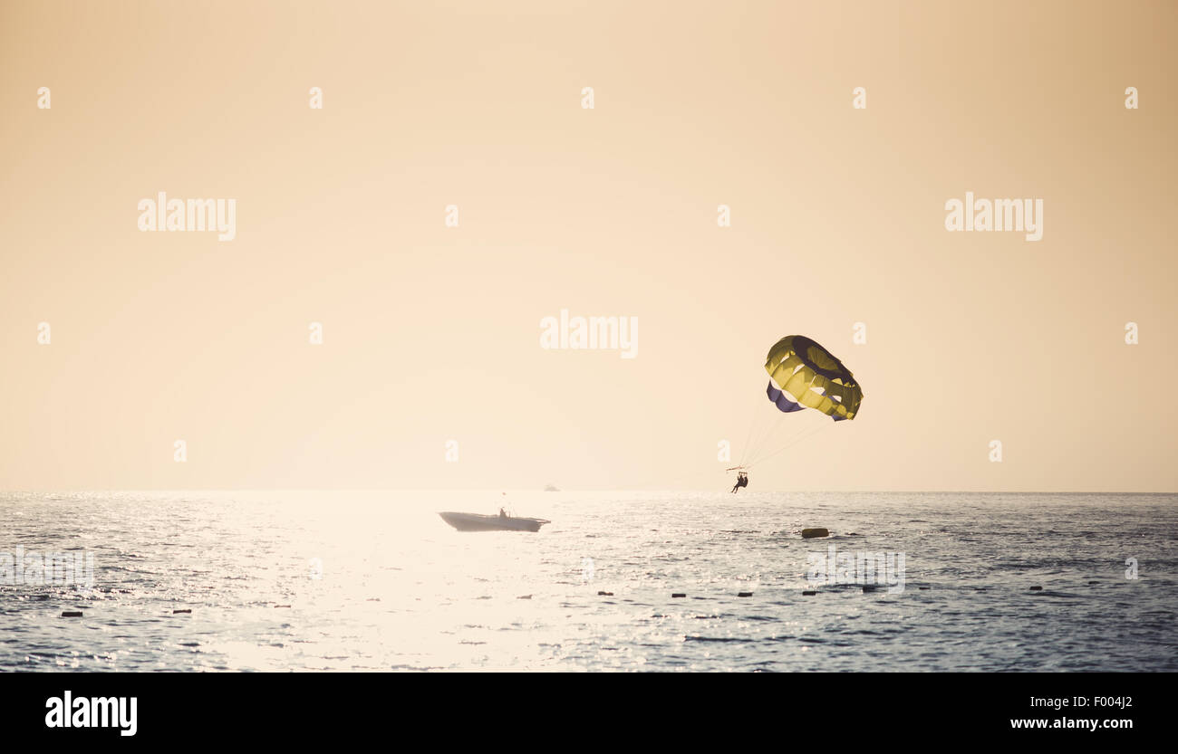 Parasailing on parachute over water at sunset Stock Photo