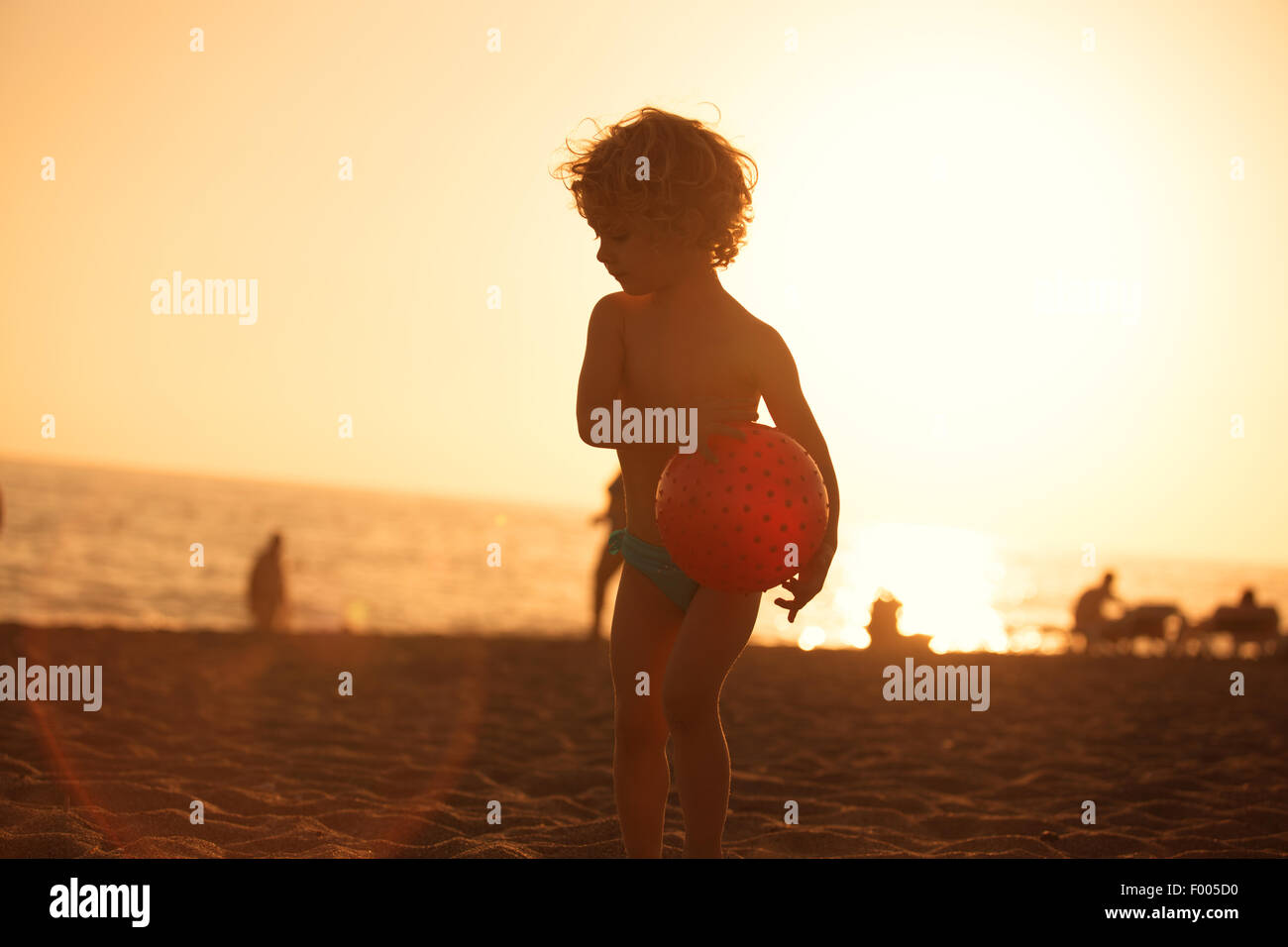 Summer vacation - little girl playing on sandy beach at sunset Stock Photo