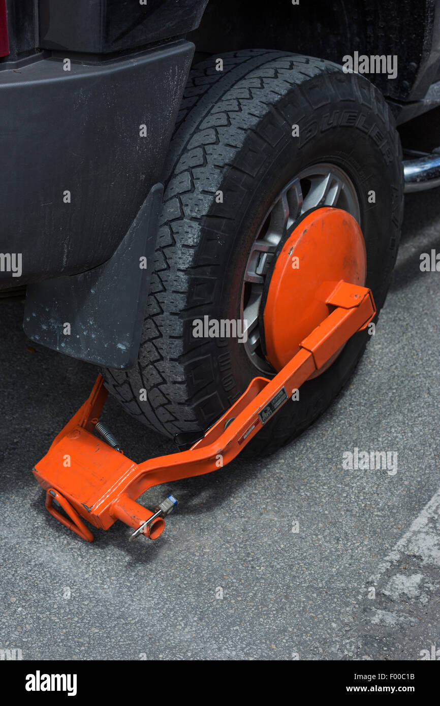 ORANGE AUTOMOBILE WHEEL CLAMP ON JEEP SPORT UTILITY VEHICLE Stock Photo