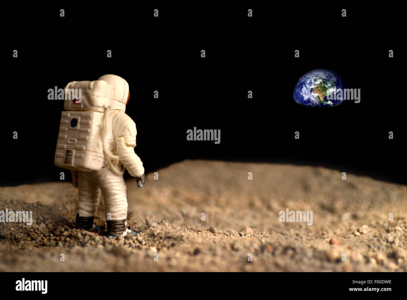 American Astronaut on the moon looking at earth on the background, elements of this image furnished by NASA. Stock Photo
