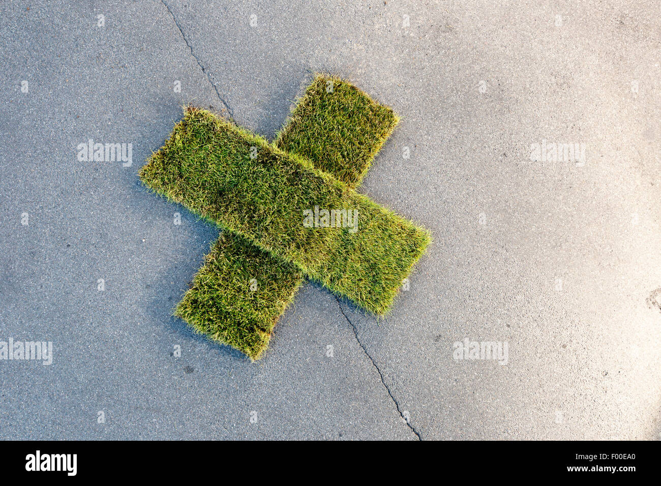 patch cross made of rolled sod on tarmac Stock Photo