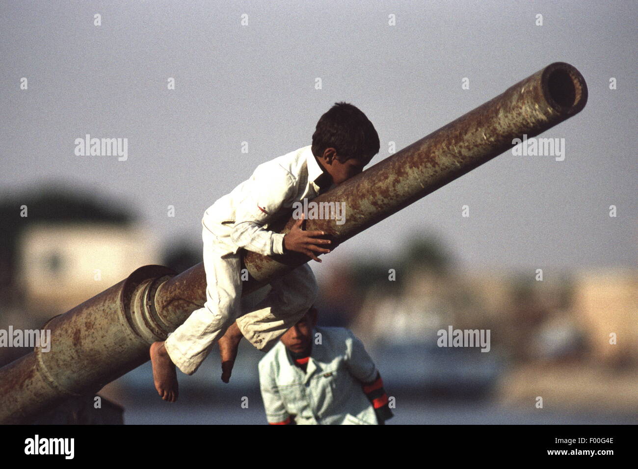 Suez Canal, Egypt - Egyptian children play on a ruined tank at the southern end of the Suez Canal, witness to wars past between Egypt and Israel.   The Suez Canal was closed to shipping from 1967 until the late 1970s, due to the debris of sunken ships in the canal.  One of the marvels of engineering constructed in 1869 by Frenchman Ferdinand de Lesseps, it is today undergoing a signficant upgrade by adding a parallel canal to increase two-way shipping traffic and lessen waiting times. Stock Photo