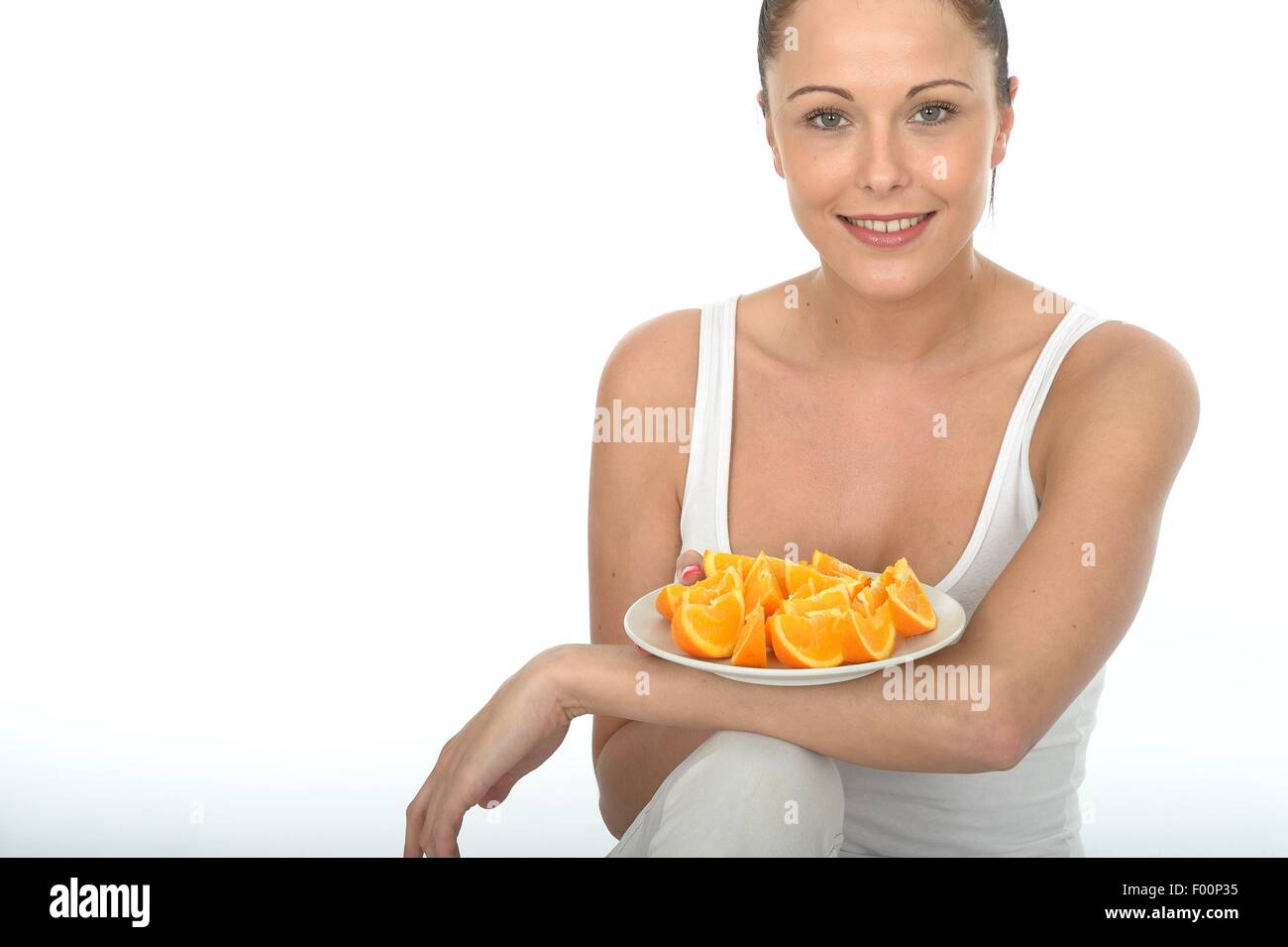 Positive Young Woman Eating Delicious Healthy Fresh Orange Fruit Segments Full Of Vitamin C Isolated Against A White Background With A Clipping Path Stock Photo