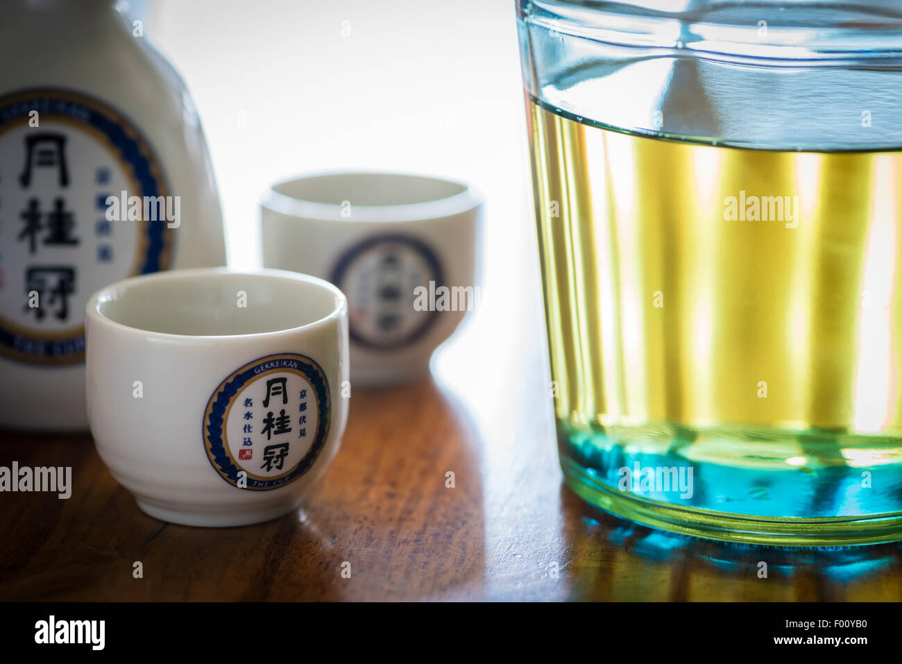 A bottle of Japanese Sake liquor, brewed by the Kyoto Sake brewery Gekkeikan, with ceramic Sake cups bearing the company logo. Stock Photo