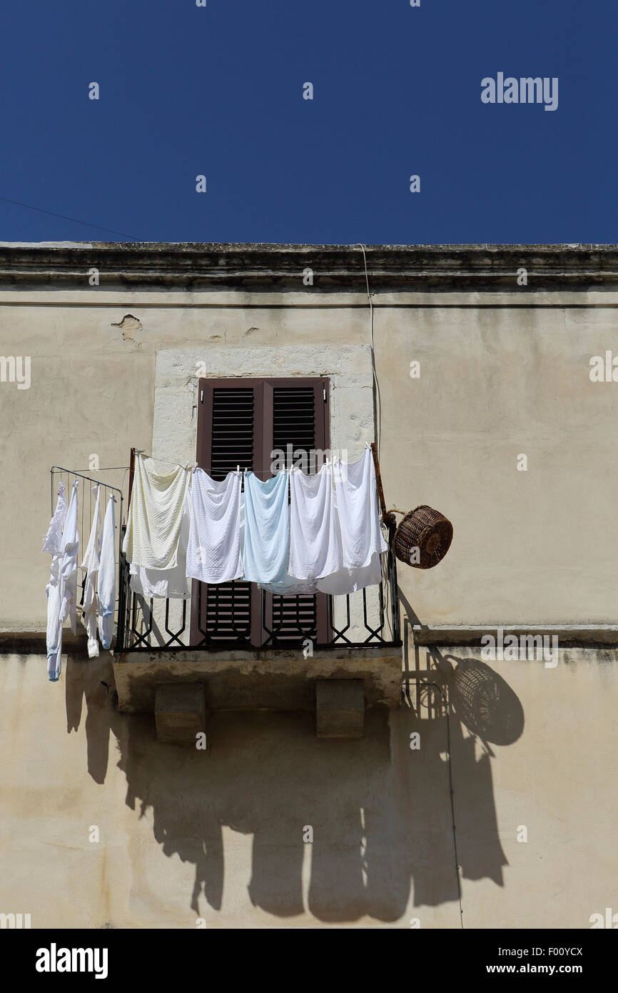 Washing dries on a balcony with a shuttered window in Trani, Italy. The scene is typical of the old Apulian town. Stock Photo