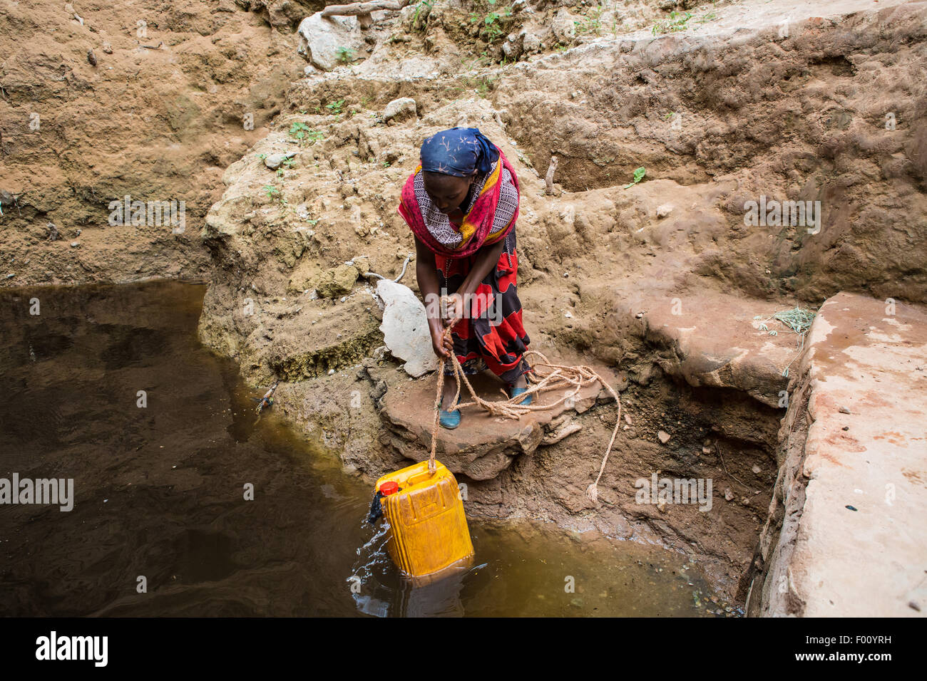 Woman takes water from a well before returning to her village. The water is purified with tablets before drinking Stock Photo