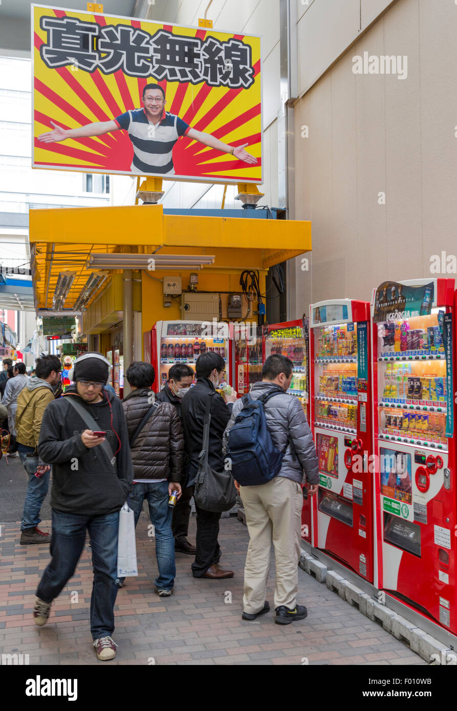 Japanese men study cell phones and vending machines in an alley in the Akihabara Electric Town Stock Photo