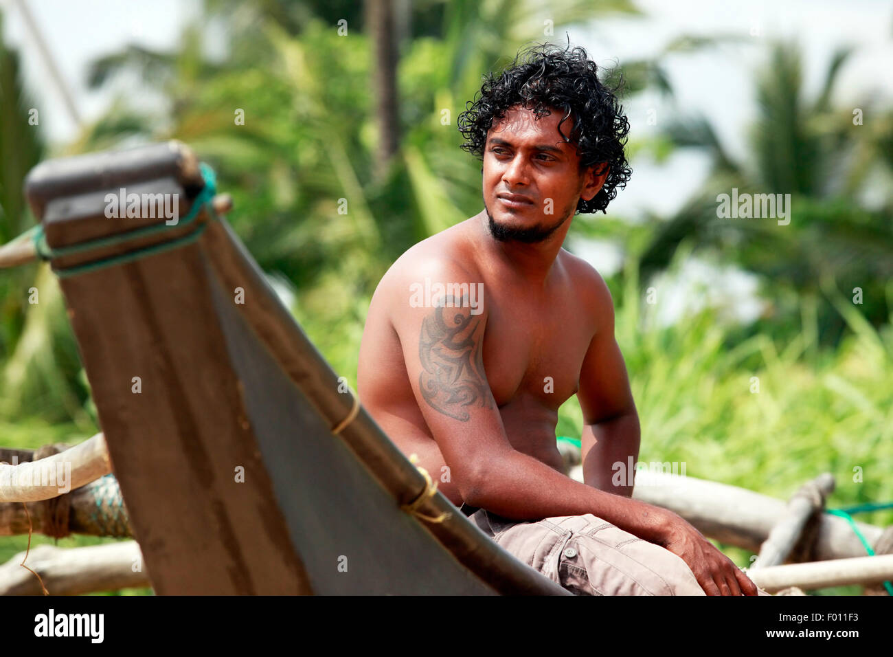 The young man sitting by a boat. Sri Lanka Stock Photo