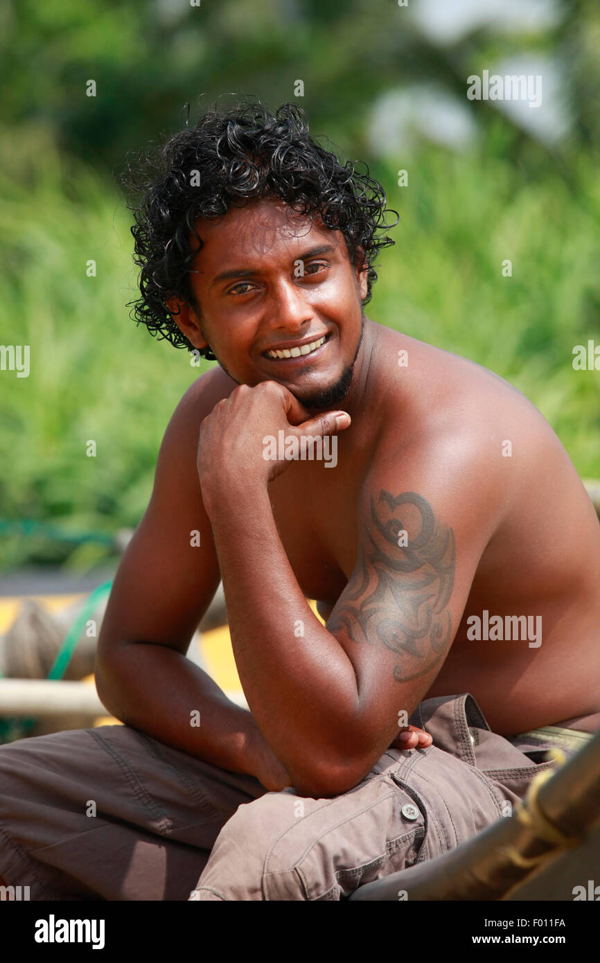 The young man sitting by a boat. Sri Lanka Stock Photo