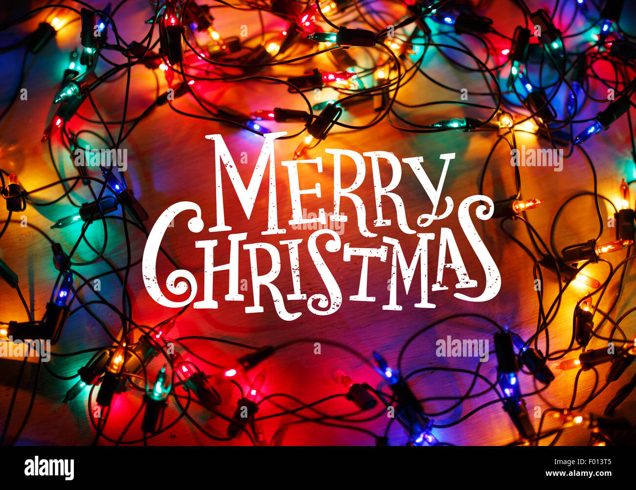 Christmas lights frame on wood background with Merry Christmas lettering. Stock Photo