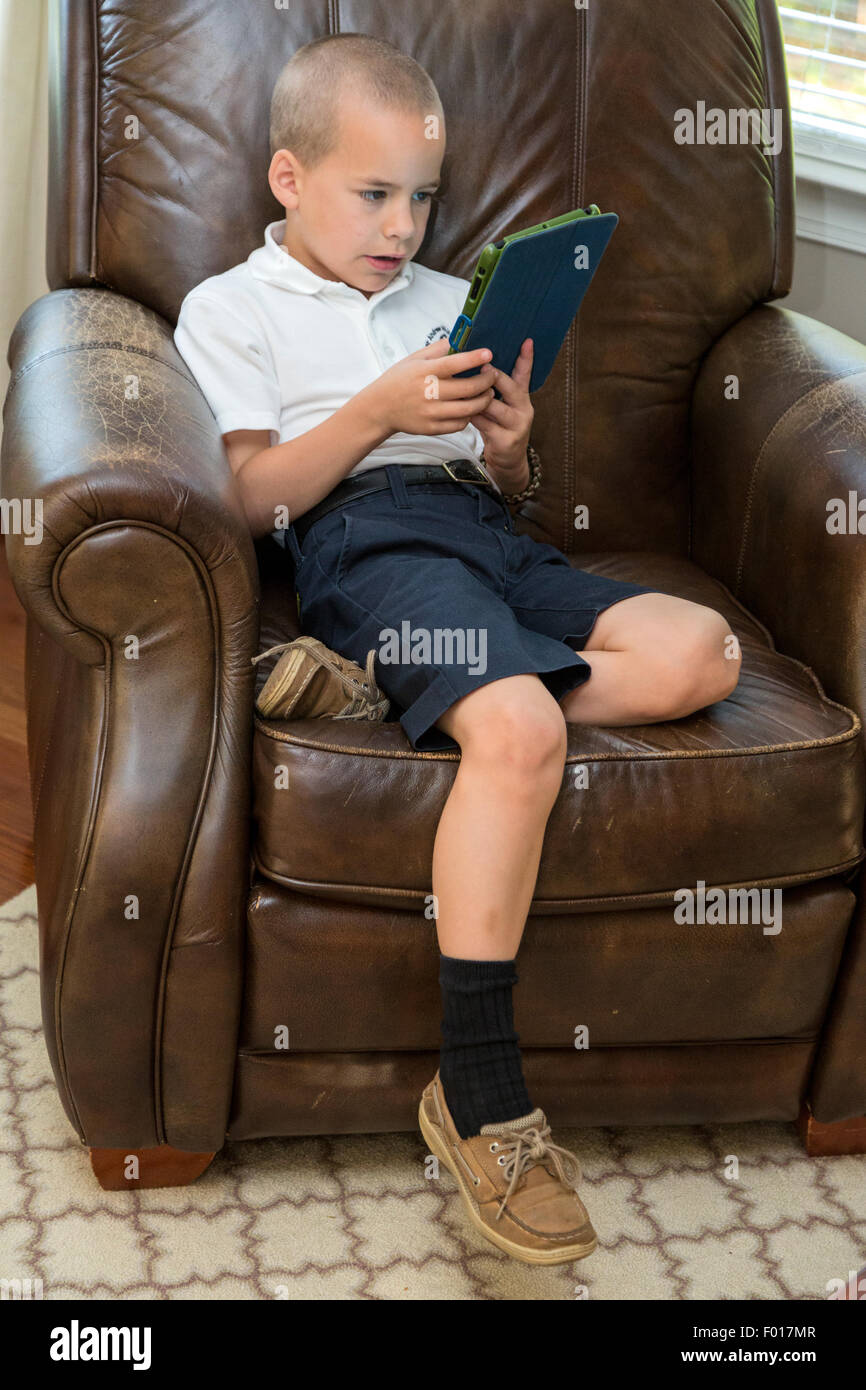 Young Boy (Seven Years Old) Engrossed in a Game on his iPad.  MR Stock Photo