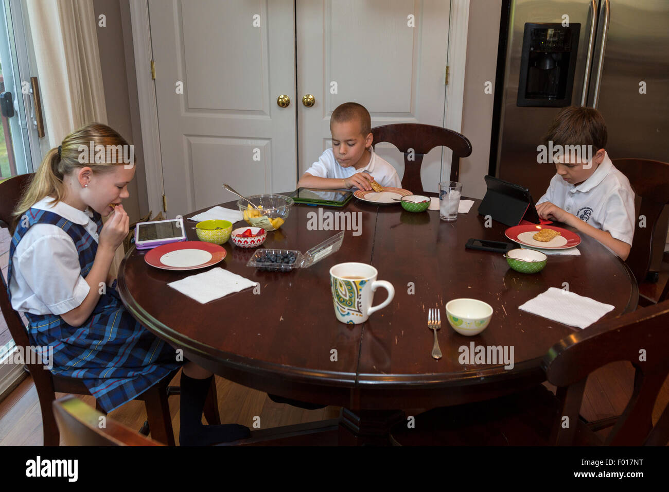 Modern Elementary School Students at Breakfast, Playing Games on their iPads.  MR Stock Photo