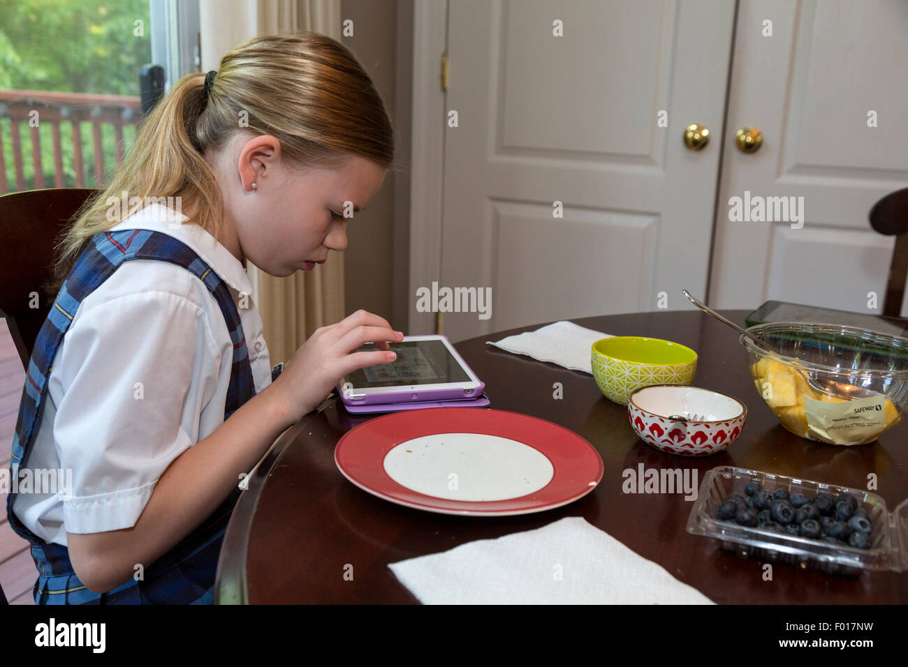 Today's Modern Elementary School Student:  Playing a game on her iPad at Breakfast.  MR Stock Photo