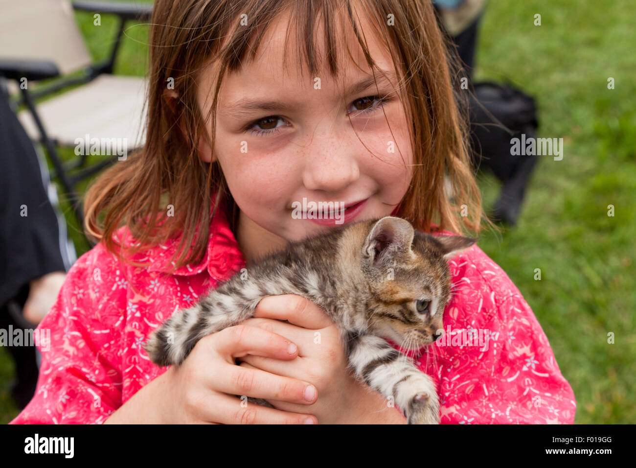 A young girl with a please can I have it look, holding a free kitten