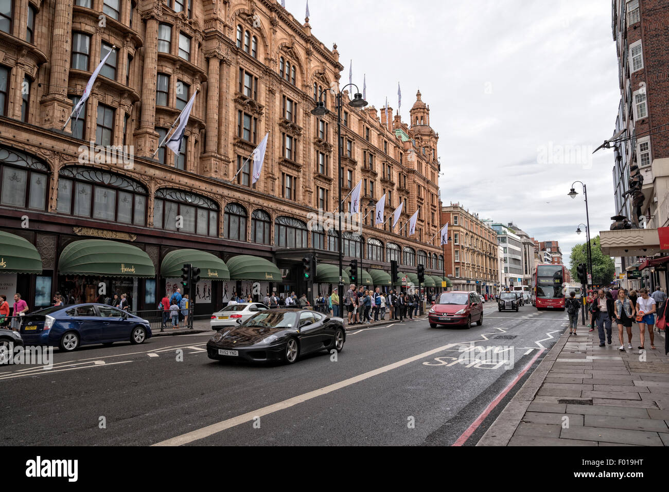 Traffic on a Rainy Sunday afternoon in the Knightbridge Section of London, England.  Harrod's Department Store in the Background Stock Photo