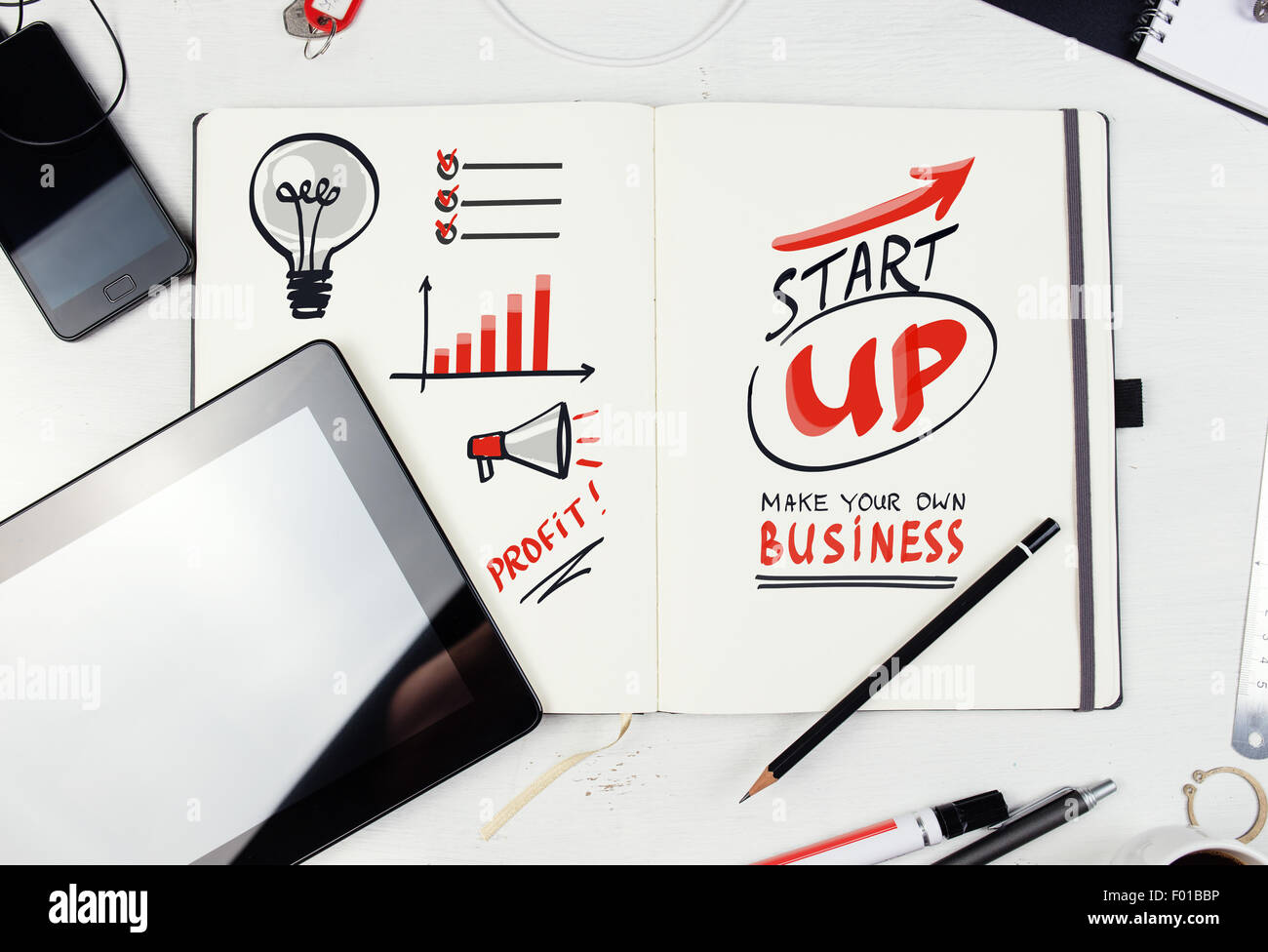 Workplace. Notepad with  Start Up lettering on table with tablet pc, mobile phone. Stock Photo