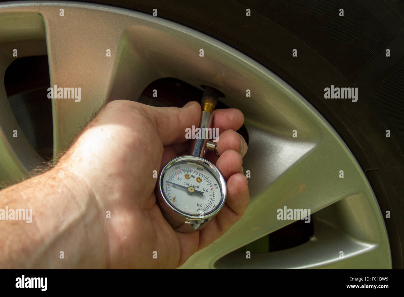 Mechanic checking air pressure levels in a car tire Stock Photo - Alamy
