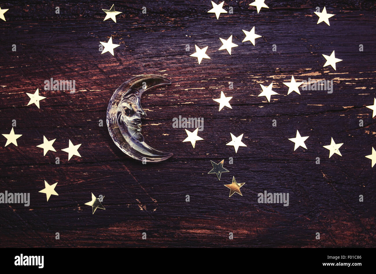 Glitter golden stars and glass moon on grunge wood background. Black