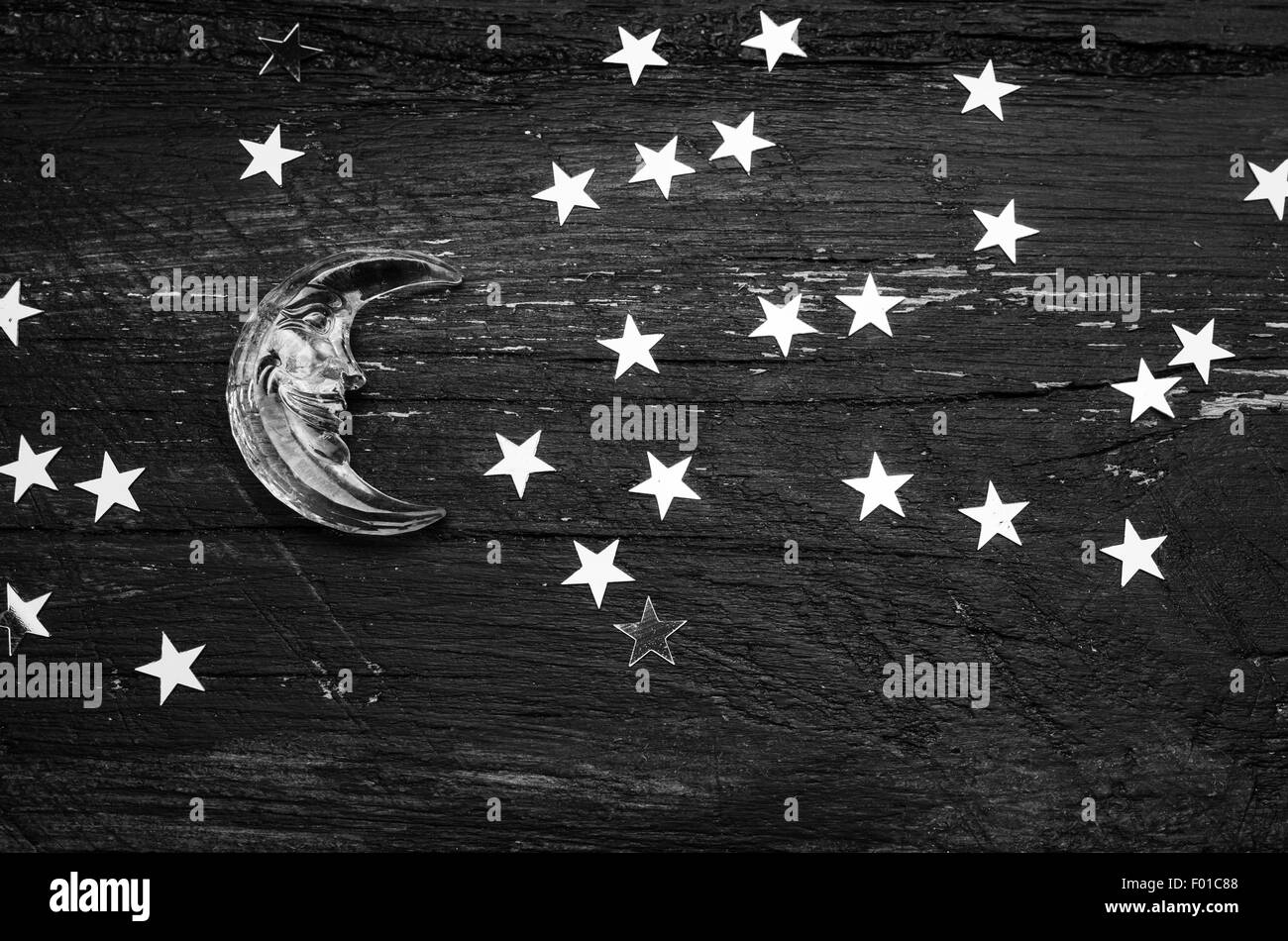 Glitter golden stars and glass moon on grunge wood background. Black and white photo Stock Photo