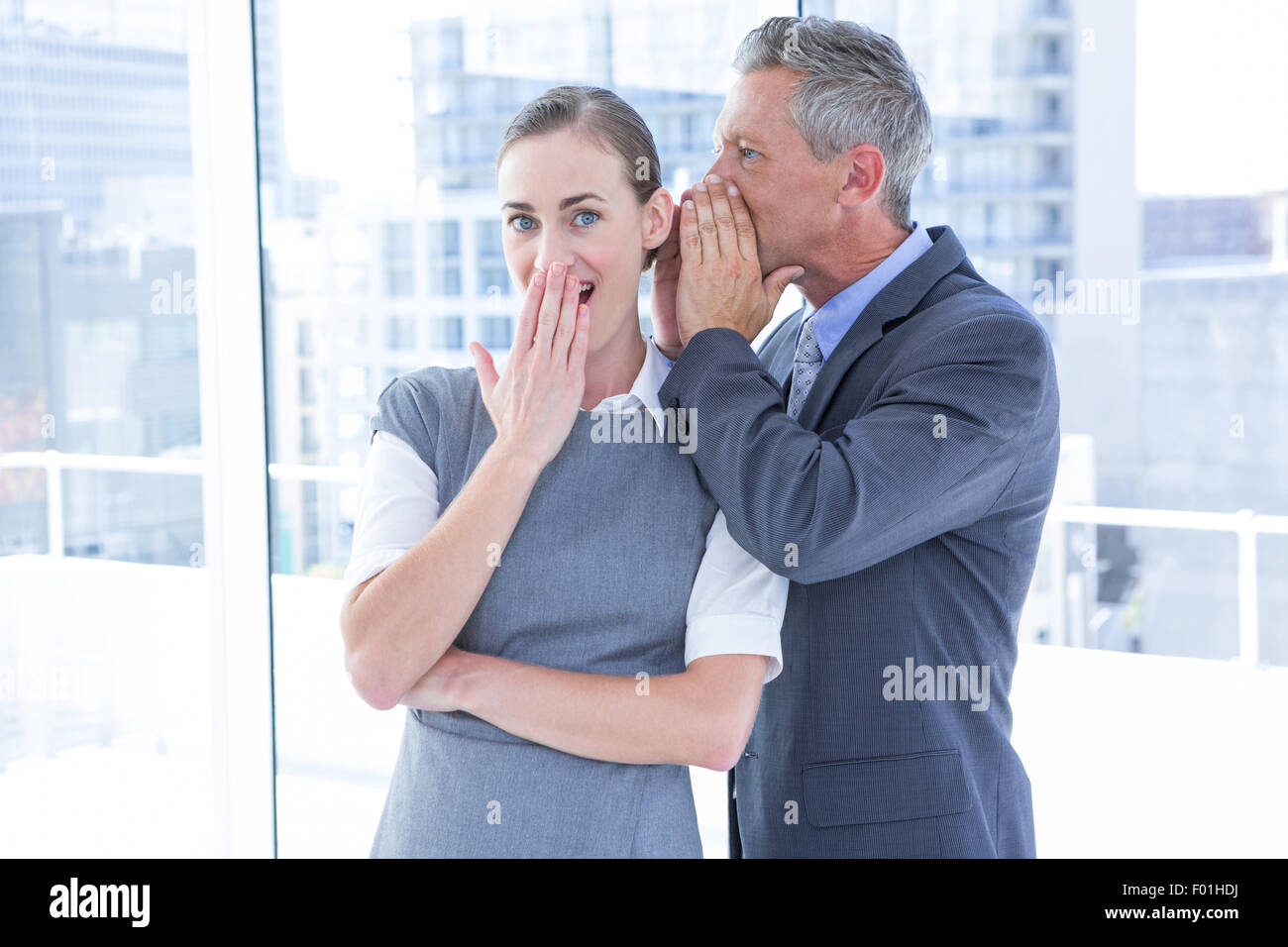 Secretive business colleagues whispering Stock Photo