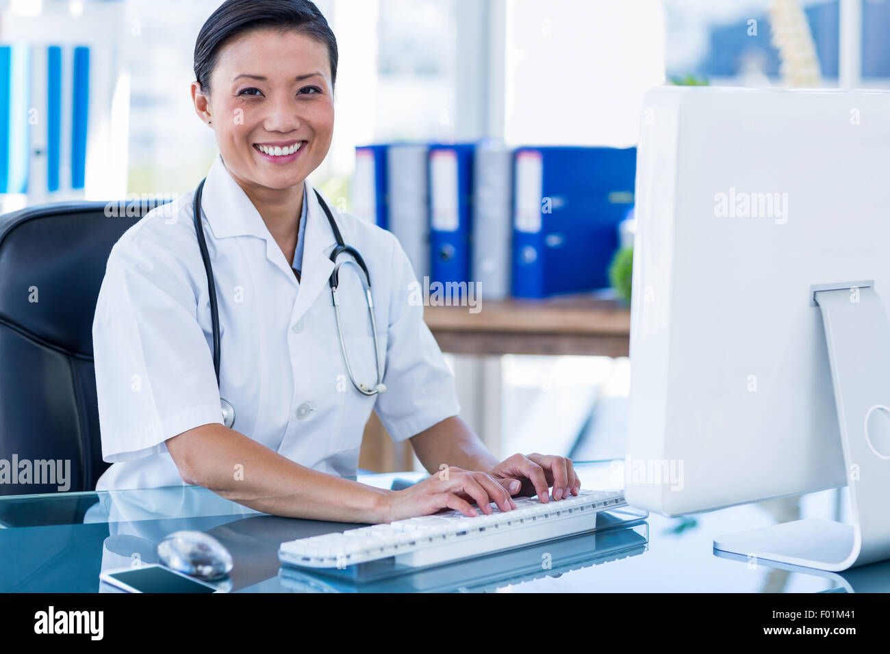 Happy doctor using her computer and looking at camera Stock Photo