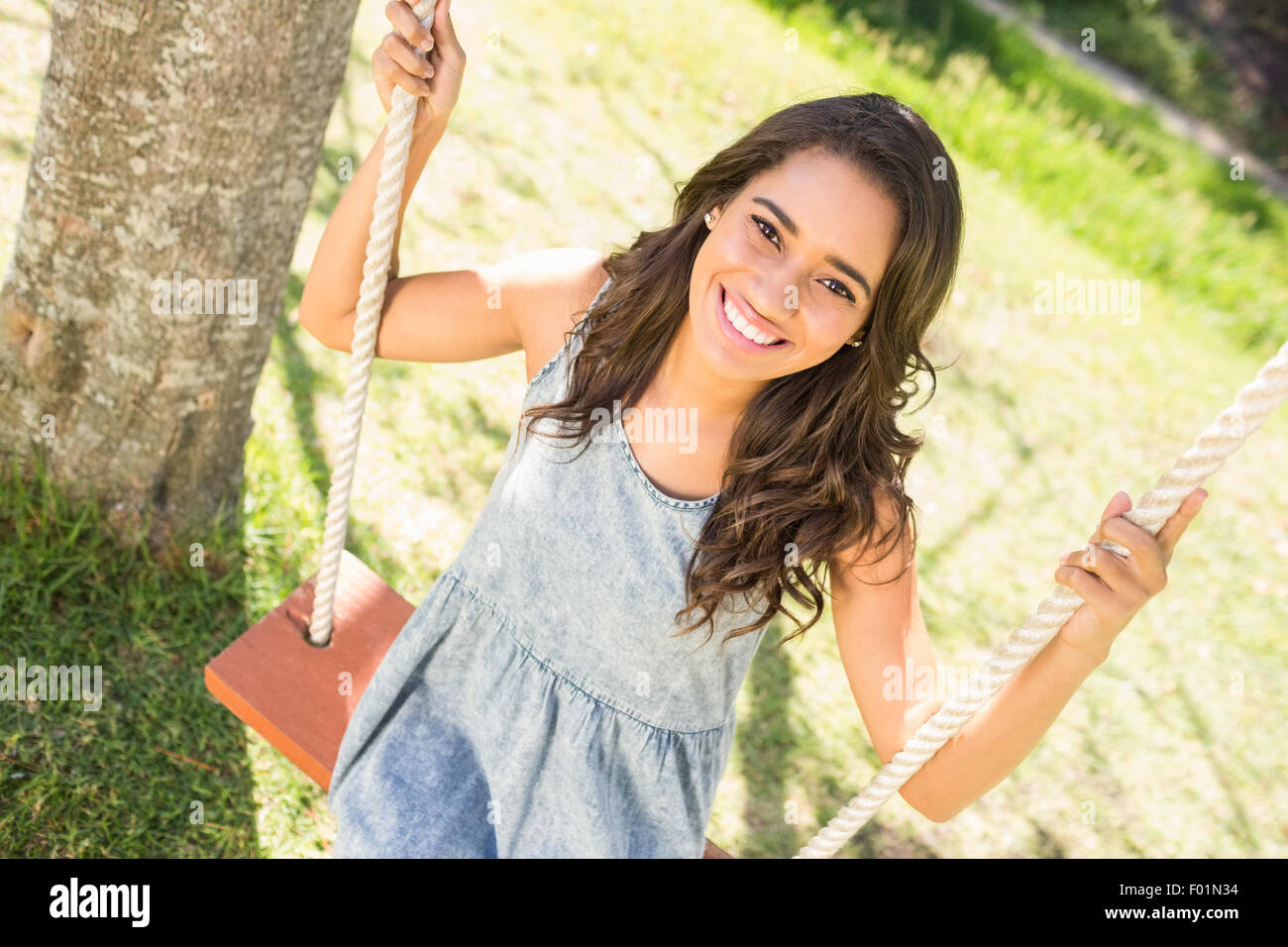 Pretty brunette swinging in park Stock Photo - Alamy