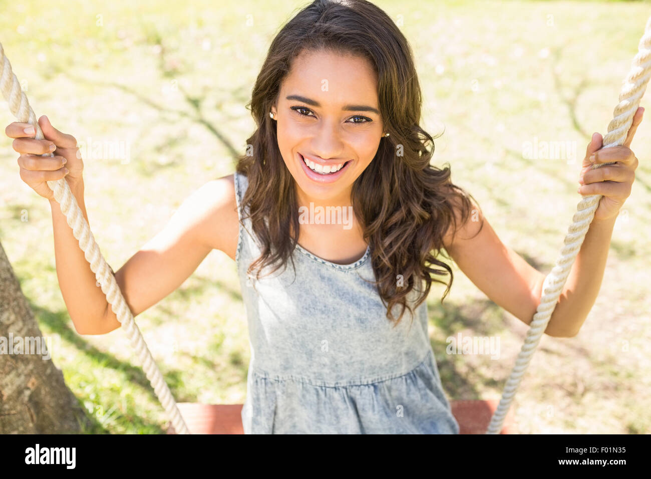 Pretty brunette swinging in park Stock Photo - Alamy