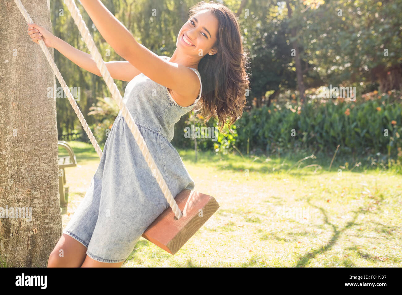 Pretty brunette swinging in park Stock Photo - Alamy