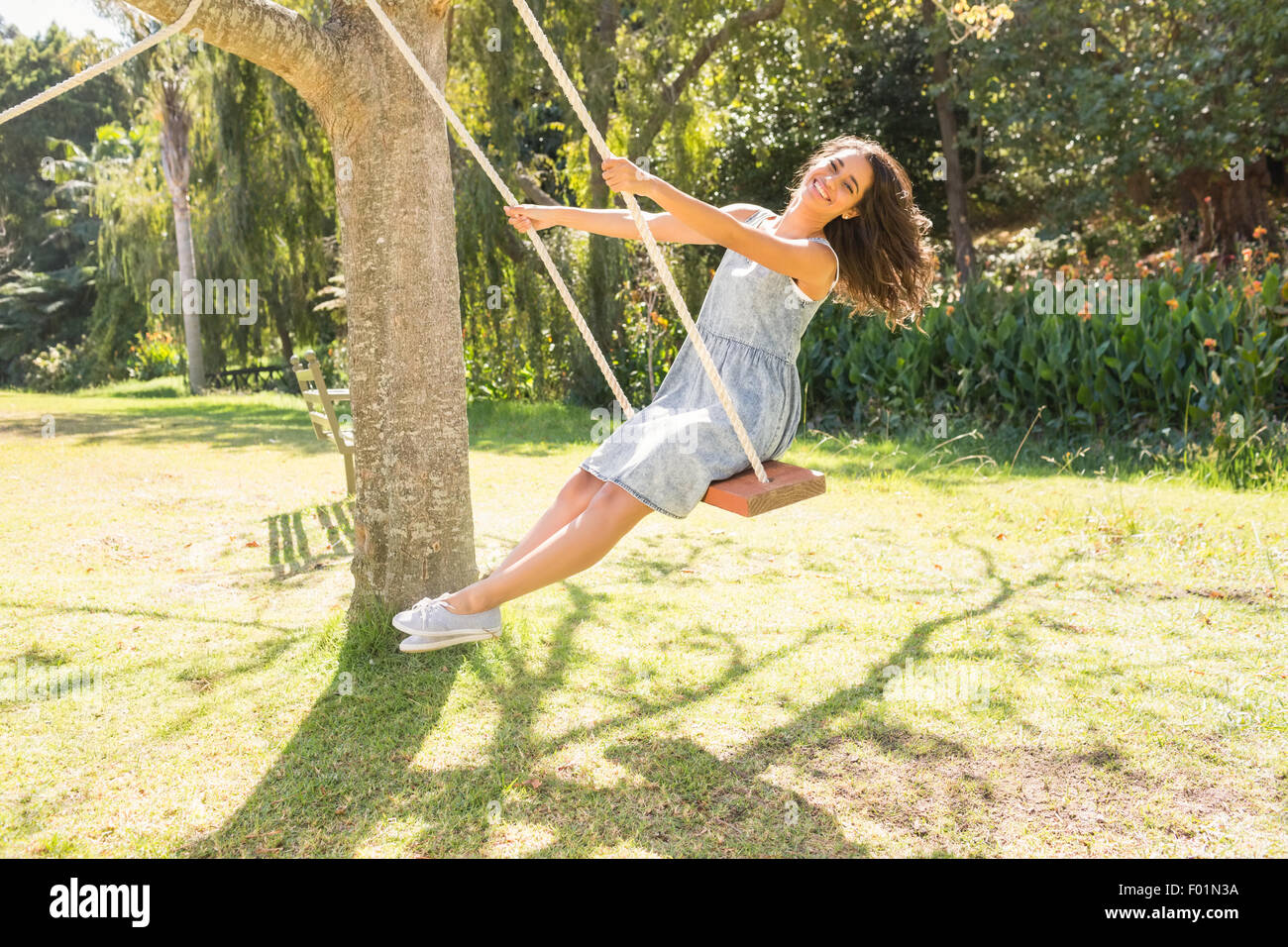 Pretty brunette swinging in park Stock Photo - Alamy