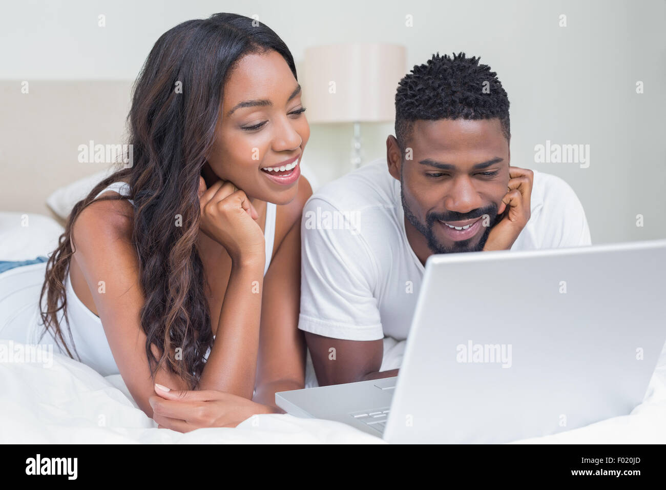 Relaxed couple using laptop on bed Stock Photo - Alamy
