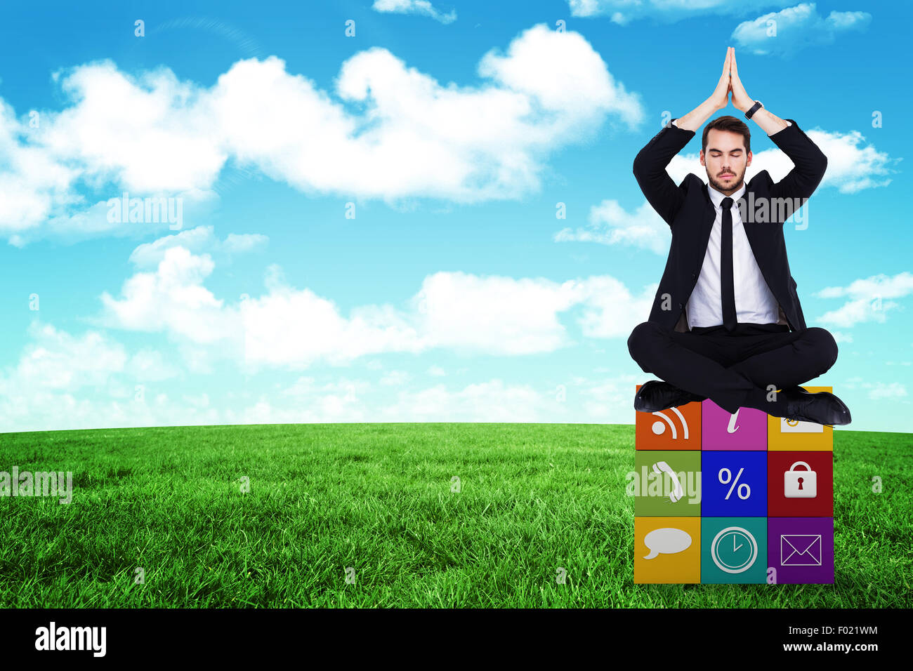 Composite image of businessman sitting in lotus pose with hands together Stock Photo