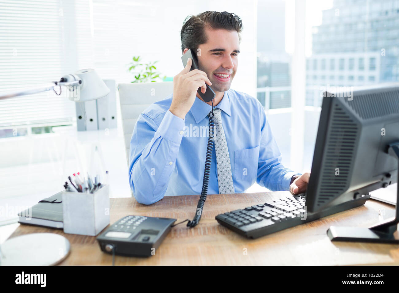 Smiling businessman using his computer ans phoning Stock Photo Alamy