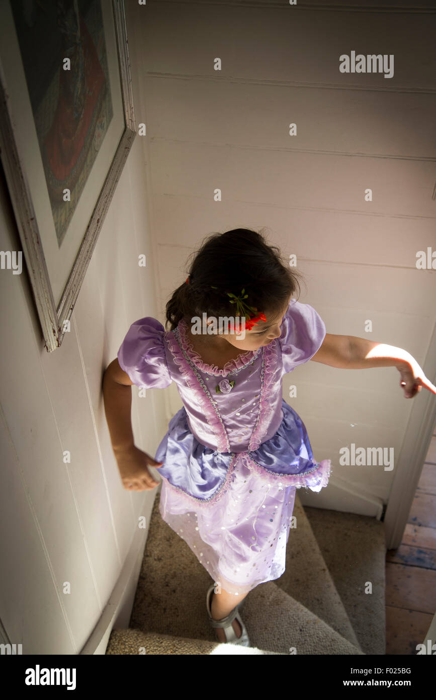 Five years old girl in a fancy-dress party climbing the stairs Stock Photo