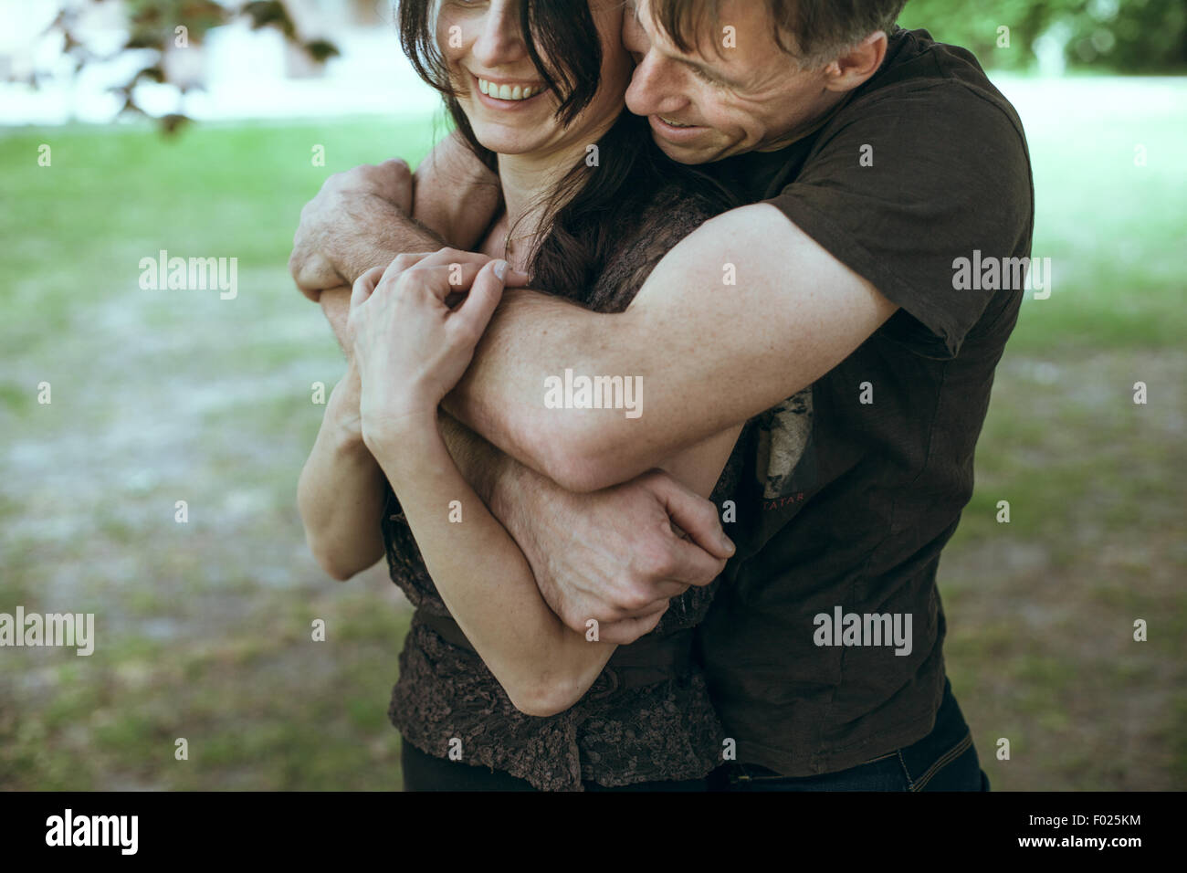 Couple standing in park hugging Stock Photo