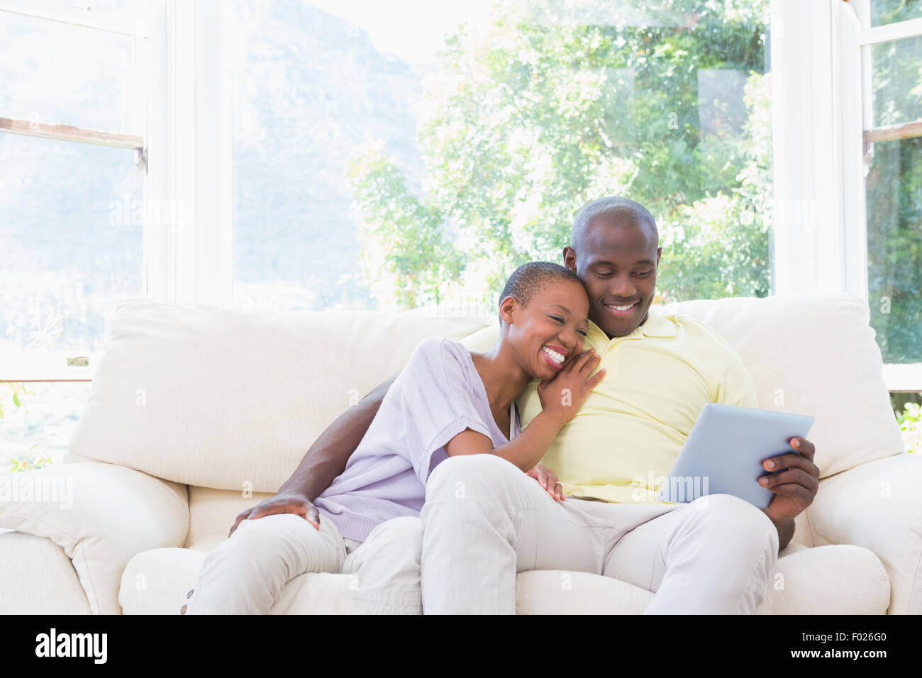 Happy smiling couple using laptop on couch Stock Photo - Alamy