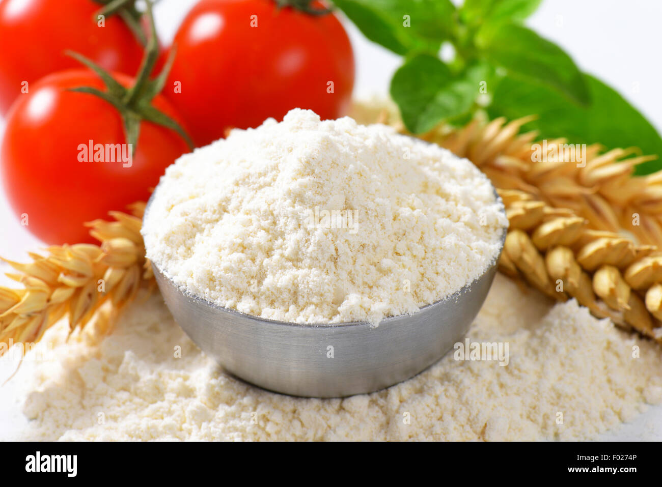 Bowl of finely ground flour, wheat ears and fresh tomatoes - still life Stock Photo