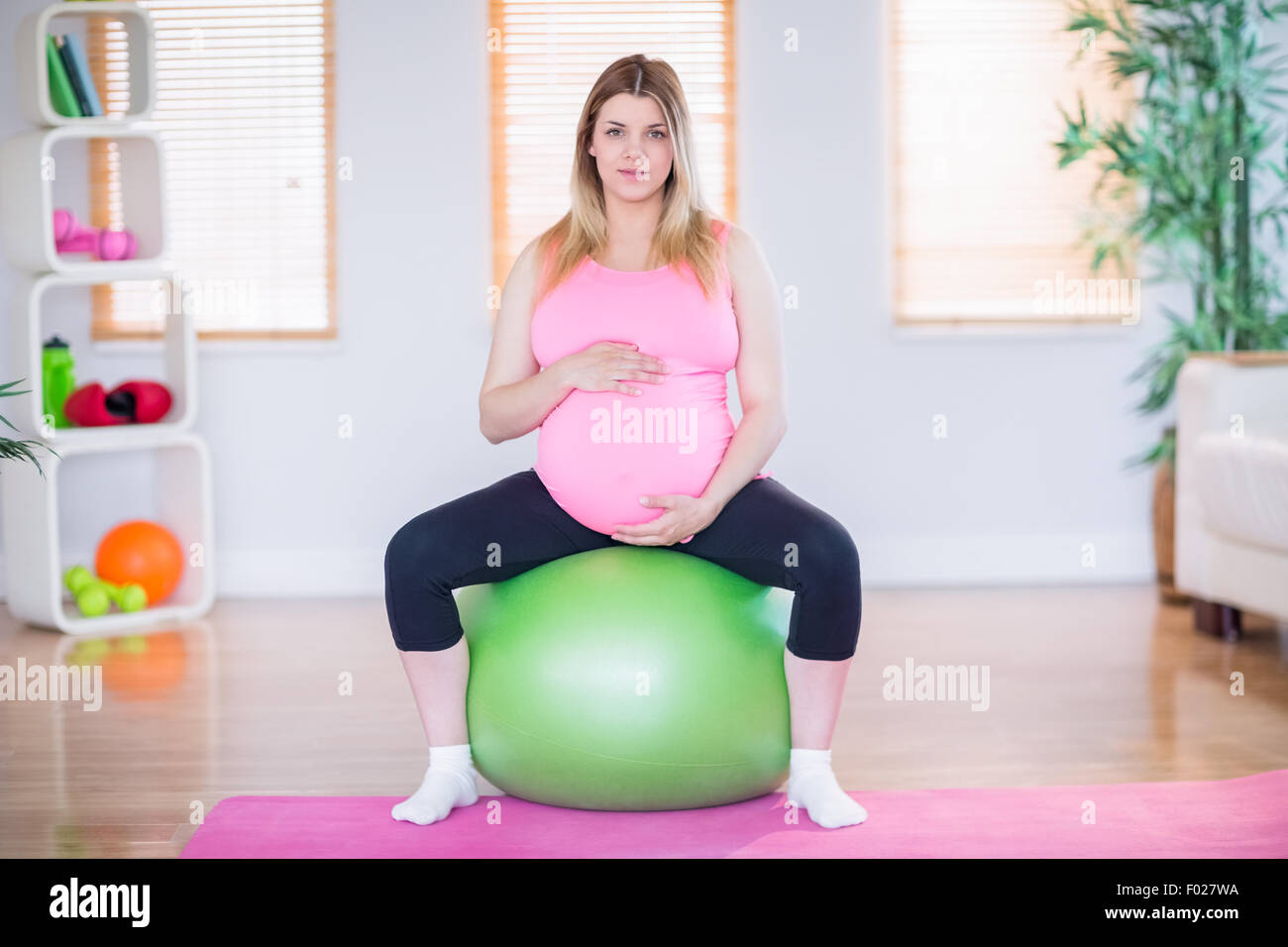Pregnant woman looking at camera sitting on exercise ball Stock Photo ...
